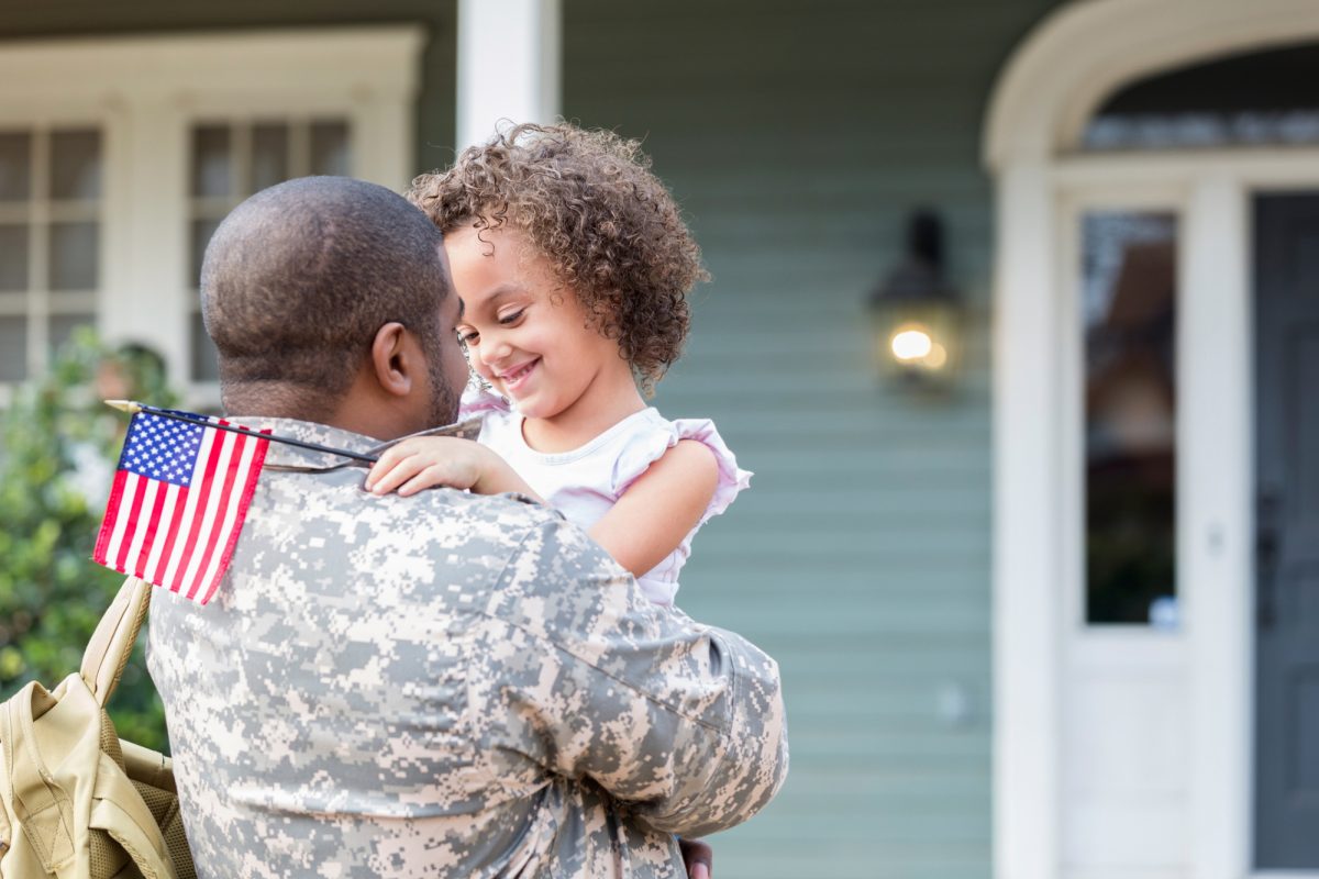 soldier-with-kid-in-front-of-house.jpg